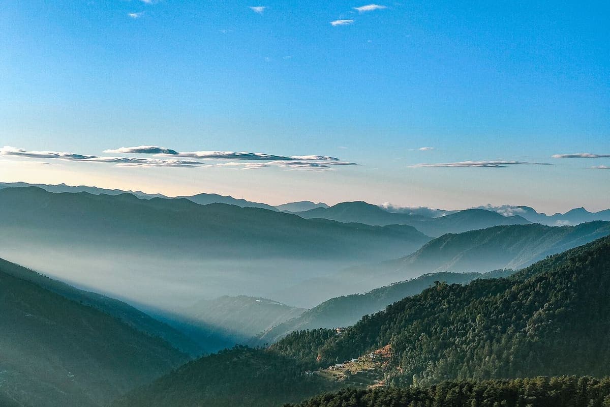 An aerial view over dense green forest covering the ridges around Chail