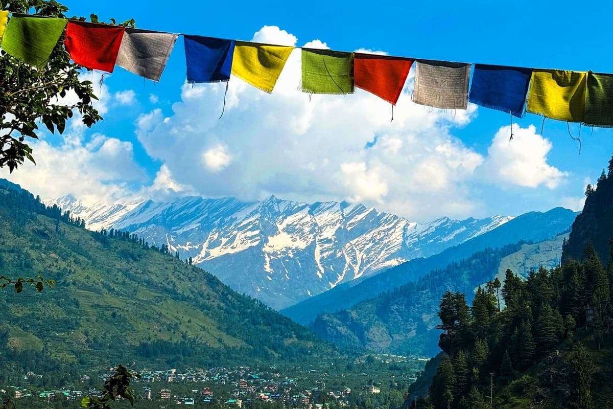 Colourful prayer flags strung in the foreground with snow-capped Himalayan peaks behind