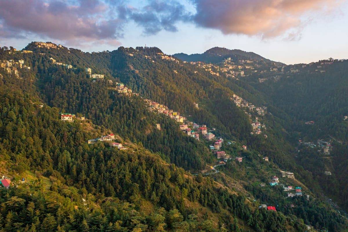 Houses scattered across steep green mountainsides at sunrise, with ridgelines receding into haze