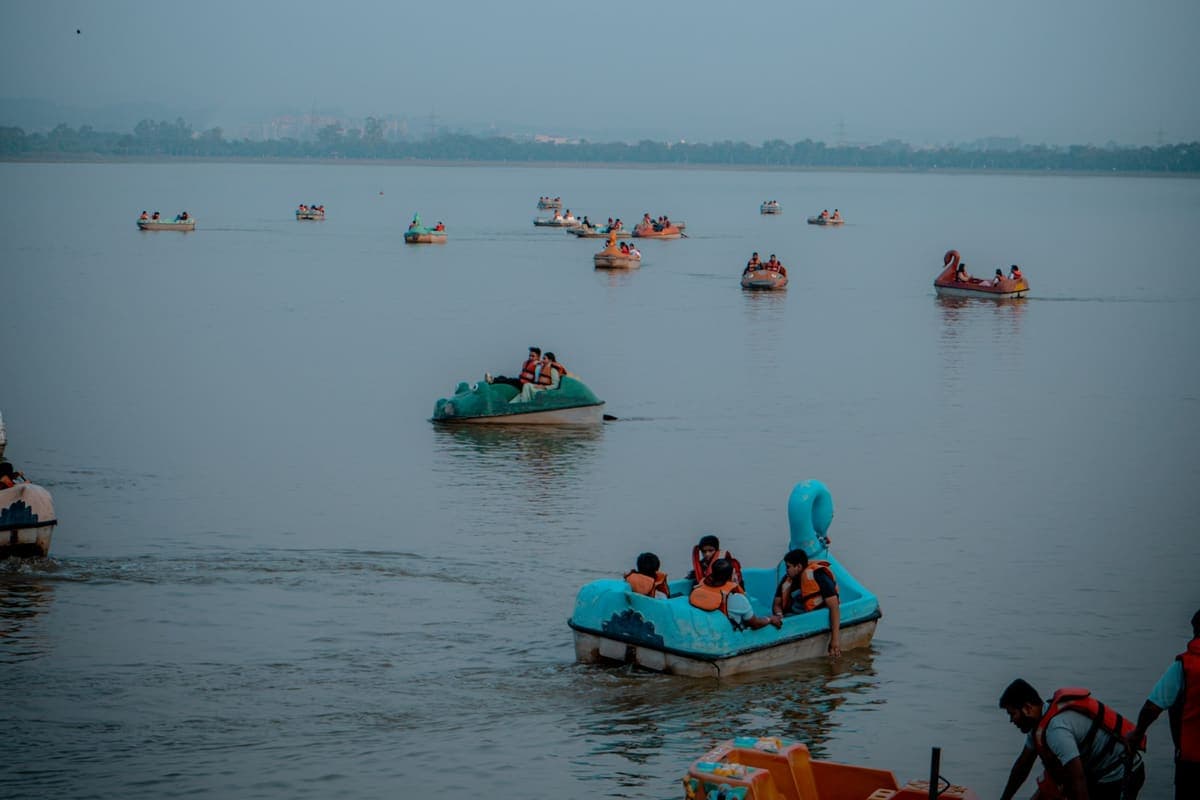 Pedal boats and rowing boats out on the water at dusk, with the far bank in silhouette
